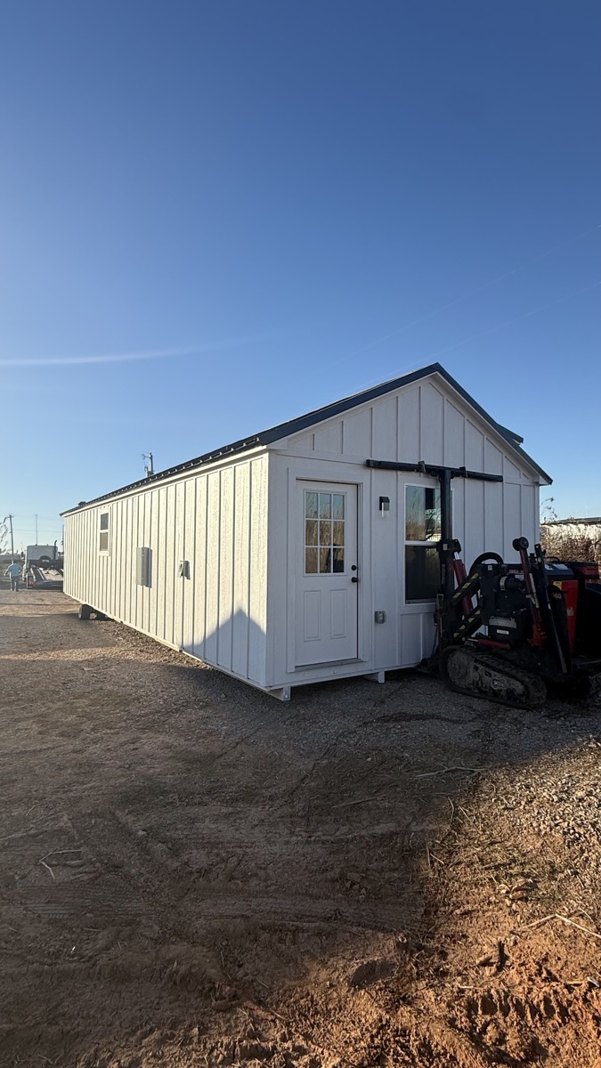 The Classic 16x44 tiny home exterior with white board and batten siding and black metal roof
