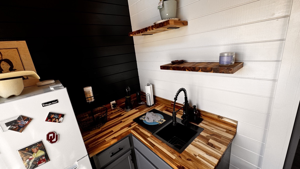 Wet bar area with butcher block counter, floating shelves and mini fridge